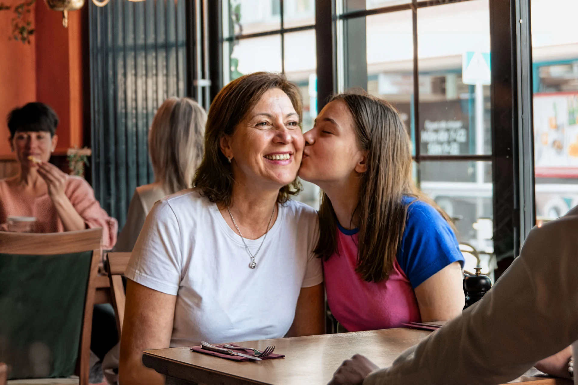 En dotter pussar sin mamma på kinden i restaurangen.